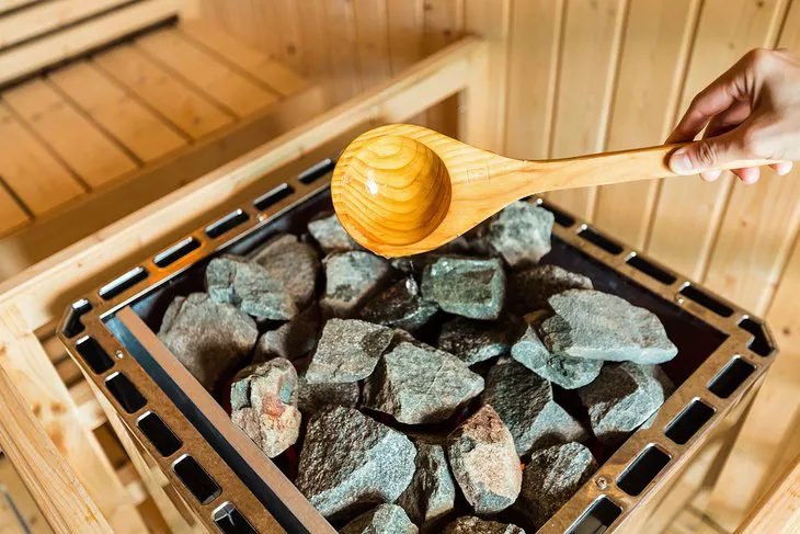 Verter agua sobre piedras calientes en una sauna