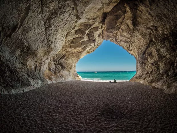 Cueva con un espectacular paisaje de playa con agua turquesa de fondo.